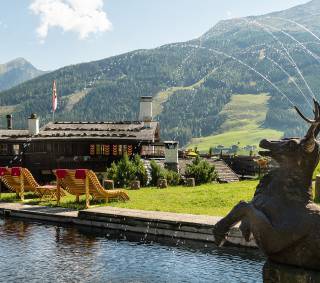 Teich mit Sonnenliegen vor Bellevue Alm Gastein